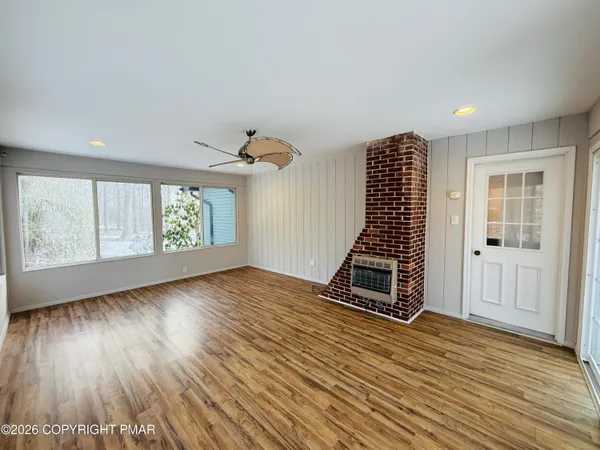 an empty room with wooden floor windows and staircase