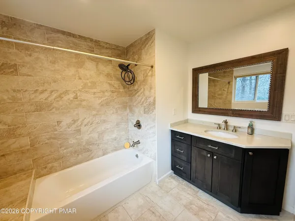 a bathroom with a tub sink and mirror