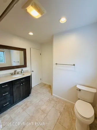 a spacious bathroom with a granite countertop toilet a sink and a mirror