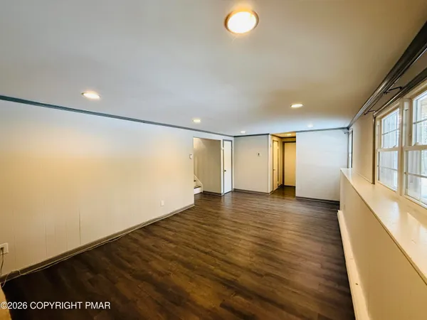 an empty room with wooden floor and windows
