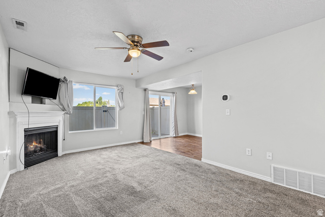 652 West 800 North, Unit 45 Clinton, UT 84015 - Photo 6 of 17 Living area featuring gray carpet, a fireplace with a white mantel, and a ceiling fan with integrated lighting