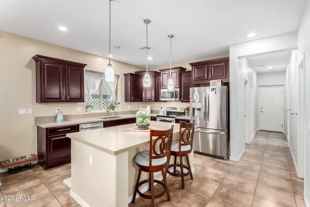 a kitchen with stainless steel appliances a refrigerator a stove a sink and a chairs