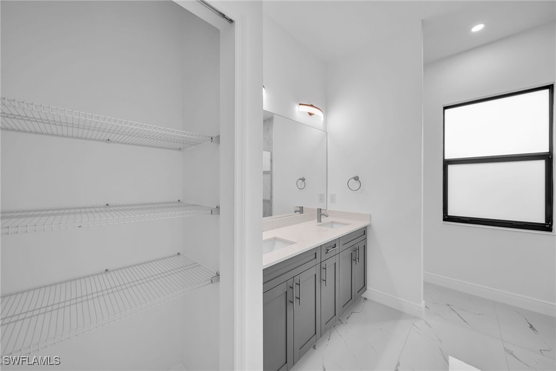 1006 West 10th Street Lehigh Acres, FL 33972 - Photo 16 of 32 a spacious bathroom with a double vanity sink a mirror and a bathtub