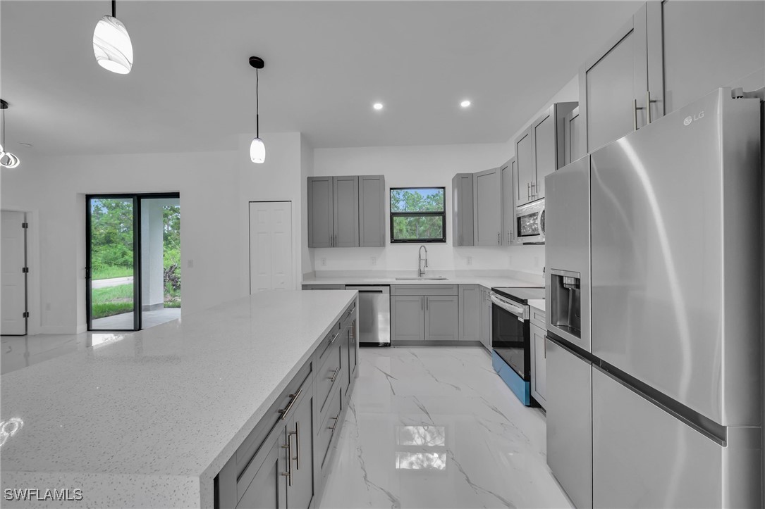 1006 West 10th Street Lehigh Acres, FL 33972 - Photo 7 of 32 a kitchen with stainless steel appliances a refrigerator sink and stove