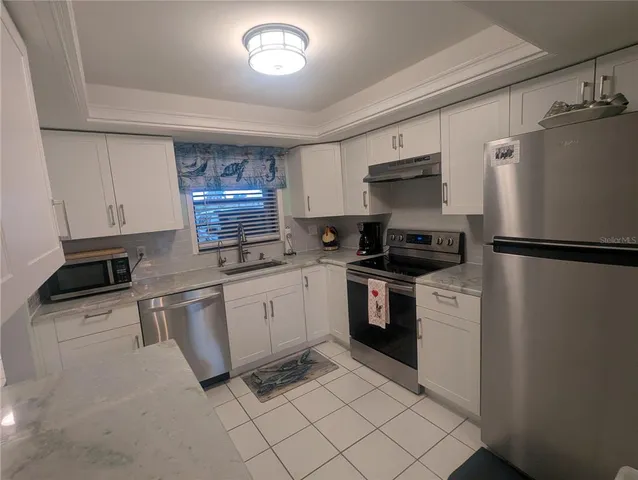 a kitchen with granite countertop a refrigerator stove top oven and sink