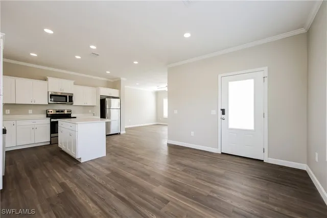 a view of kitchen with refrigerator and white cabinets