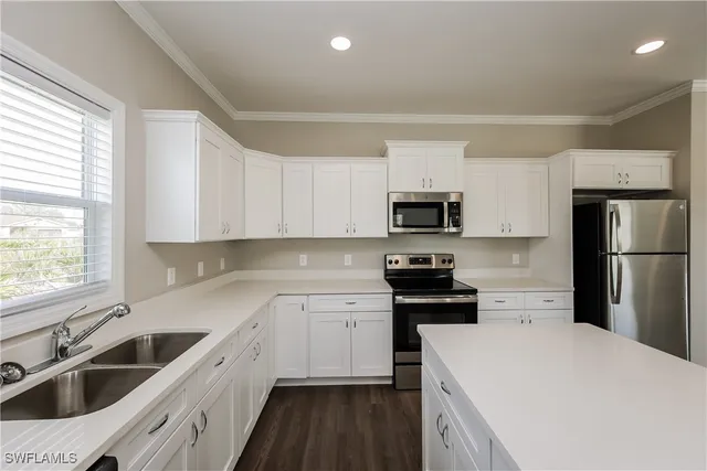 a kitchen with a sink white cabinets and stainless steel appliances