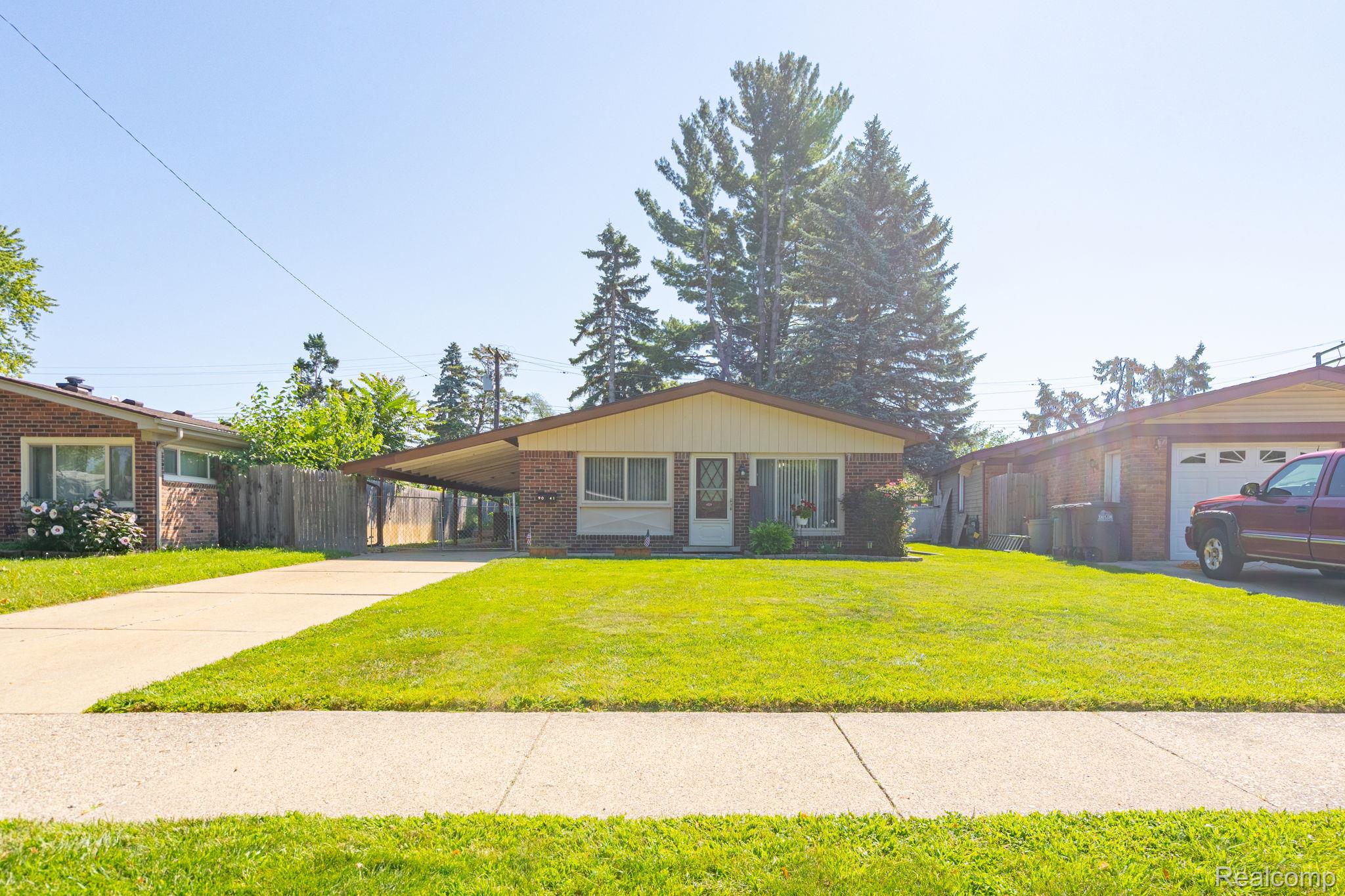 9041 Rackham Street Taylor, MI 48180 - Photo 2 of 34 Brick exterior with light-colored siding, covered carport, concrete driveway, and a front lawn