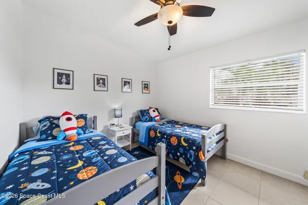 a bedroom with baby bed toys and two windows