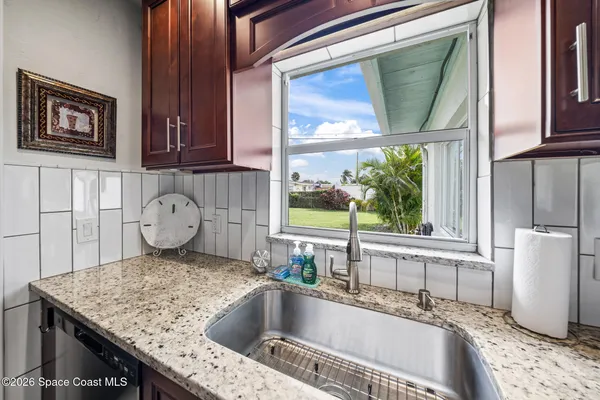 a kitchen with a granite countertop sink and a window