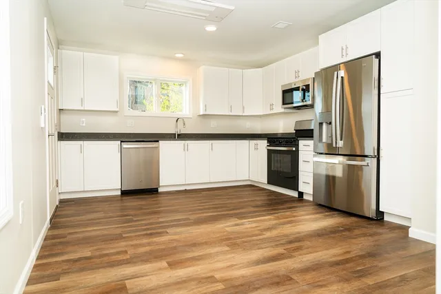 a kitchen with granite countertop a refrigerator and a stove top oven