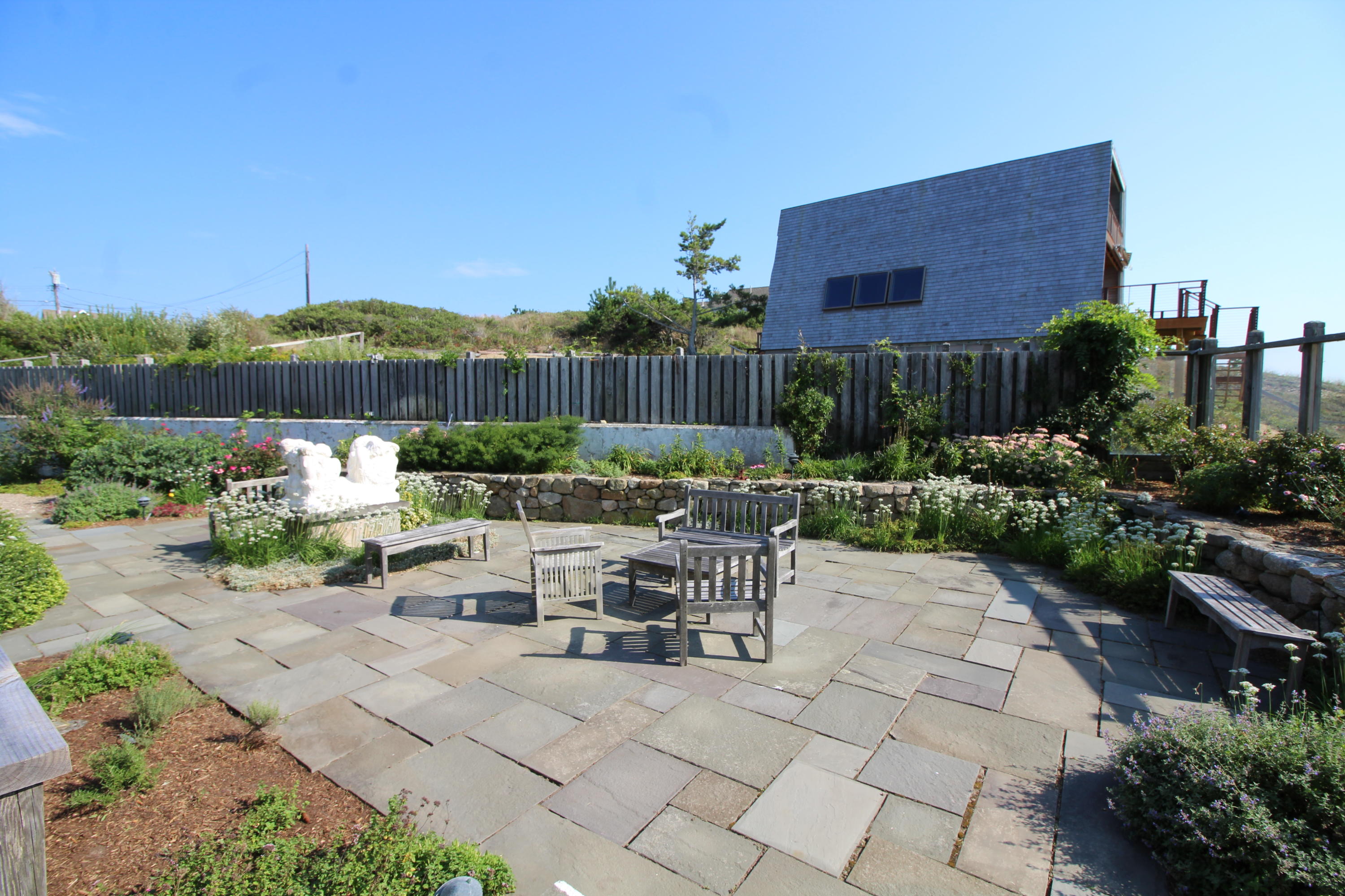 17 Bay View Road Truro, MA 02666 - Photo 8 of 40 a view of a patio with table and chairs potted plants and a small yard
