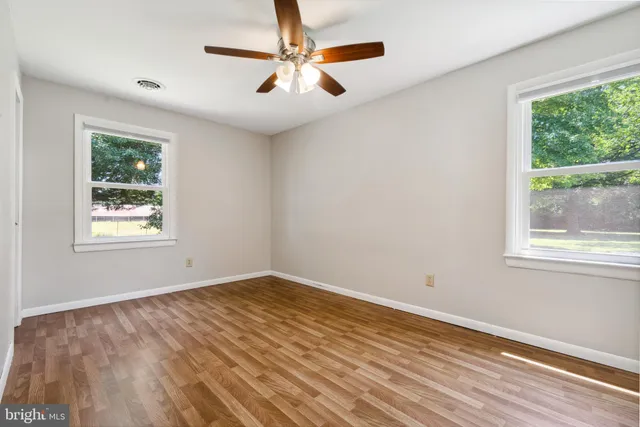 a view of empty room with wooden floor and fan