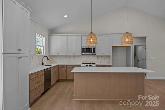 a large kitchen with stainless steel appliances granite countertop a sink a stove and a refrigerator