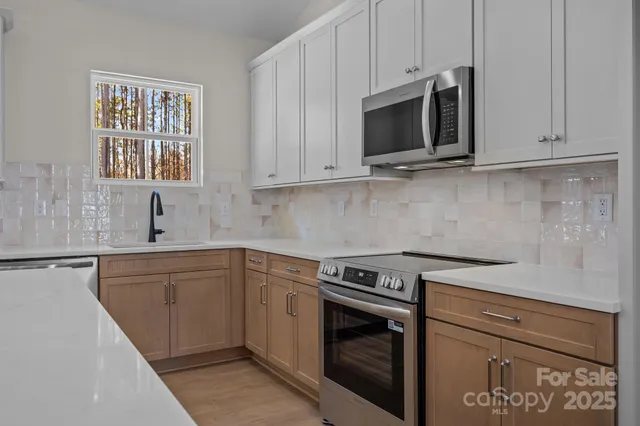 a kitchen with granite countertop white cabinets stainless steel appliances and a sink