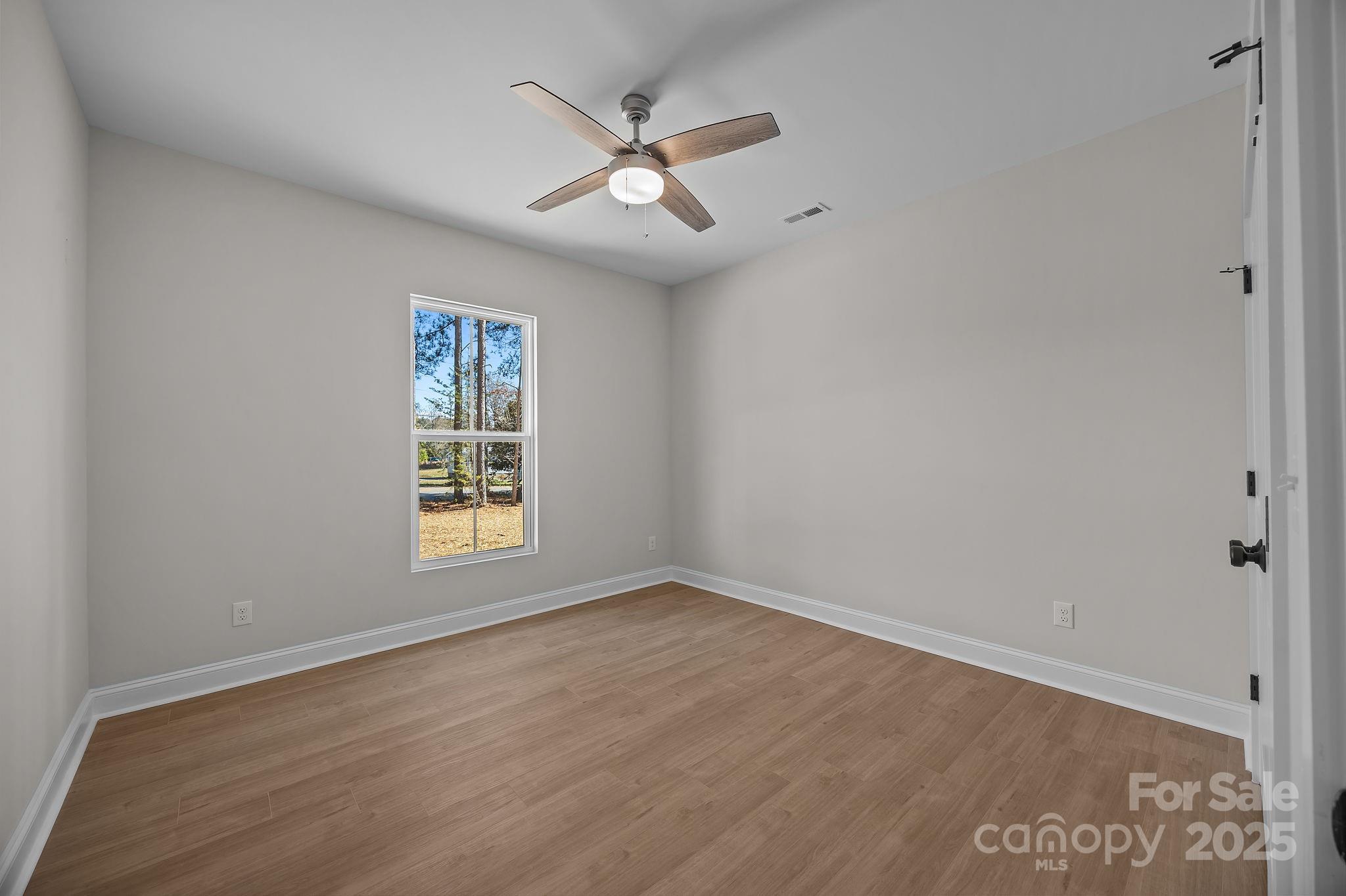 2307 Lee Lawing Road Lincolnton, NC 28092 - Photo 26 of 40 an empty room with wooden floor ceiling fan and windows