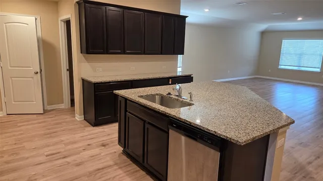 a kitchen with granite countertop kitchen island wooden cabinets a sink and dishwasher