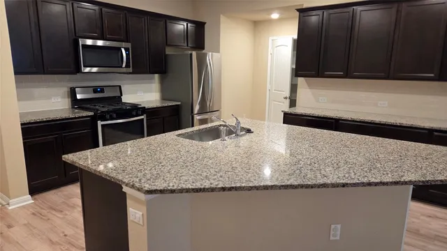 a kitchen with granite countertop wooden cabinets and stainless steel appliances