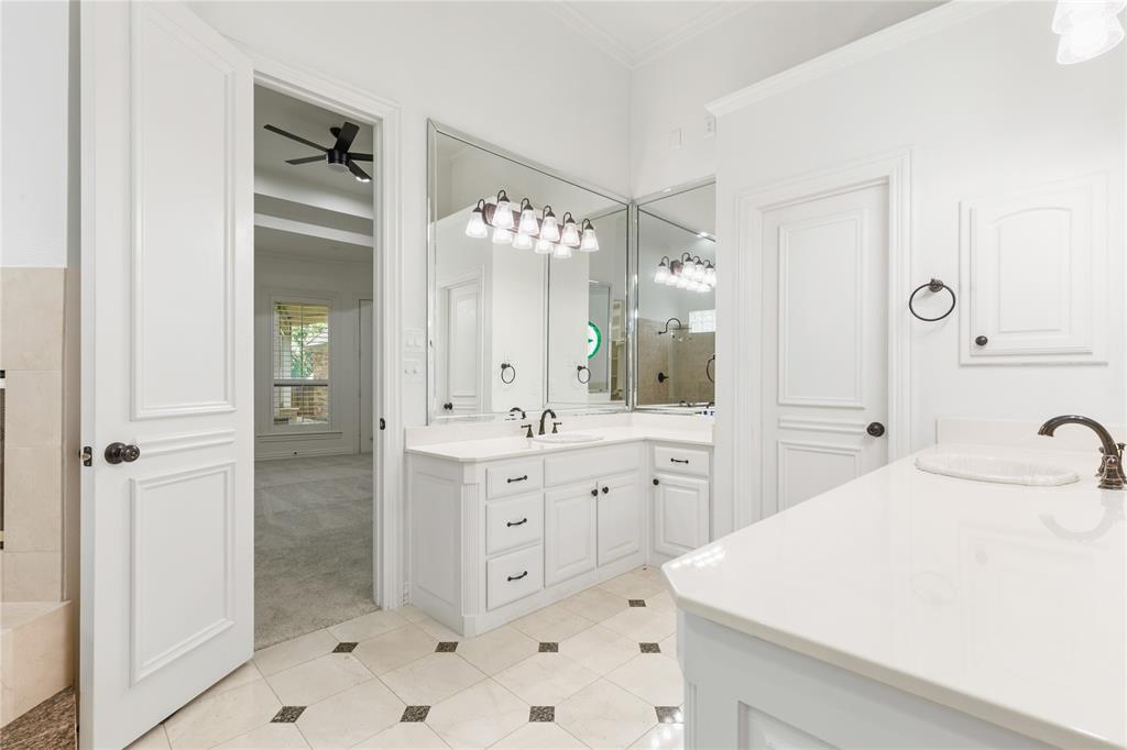 967 East Bethel School Road Coppell, TX 75019 - Photo 25 of 39 Bathroom featuring a dual vanity, extensive mirrored wall, white cabinetry with dark hardware, a separate vanity counter, and tiled flooring with dark accent squares