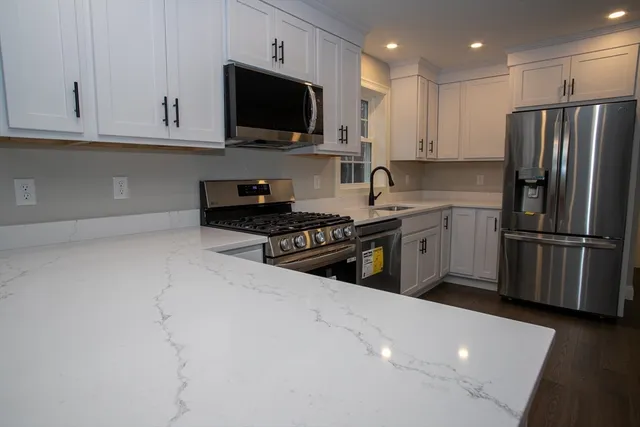 a kitchen with stainless steel appliances granite countertop a stove a sink and a refrigerator