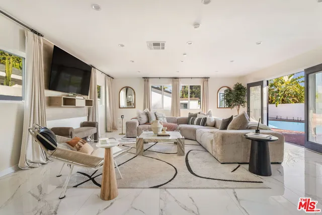 a living room with furniture a flat screen tv and large windows