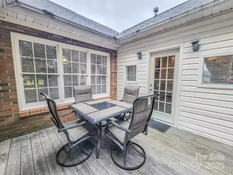 a view of a patio with table and chairs with wooden floor and fence