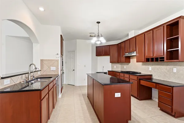 a kitchen with stainless steel appliances granite countertop a sink a stove and a refrigerator
