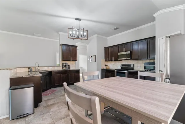 a kitchen with stainless steel appliances a stove sink microwave refrigerator and chairs