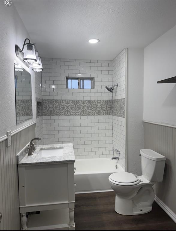 440 Rigsby Street Van Alstyne, TX 75495 - Photo 5 of 7 Full bathroom featuring a single white vanity with a marble-finish countertop, subway tile shower surround with decorative accent band, and wood-finish flooring