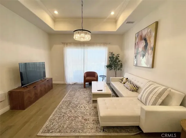 a living room with furniture a flat screen tv and a chandelier