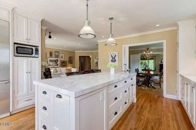 a kitchen with stainless steel appliances kitchen island granite countertop a refrigerator a stove and a wooden floors