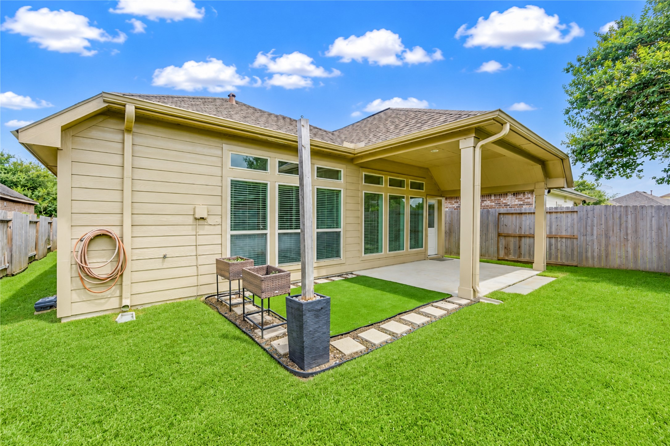 27407 Gatlin Lane Spring, TX 77386 - Photo 34 of 35 The rear exterior showcases the home's expansive windows and covered patio, highlighting the thoughtful design and inviting outdoor space ready for year-round enjoyment.
