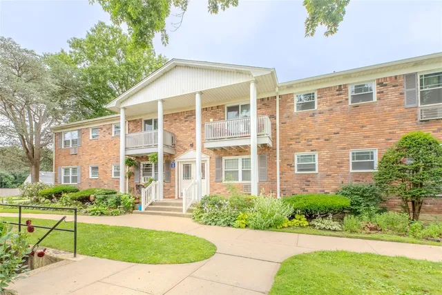 a view of a brick house with a yard and large trees