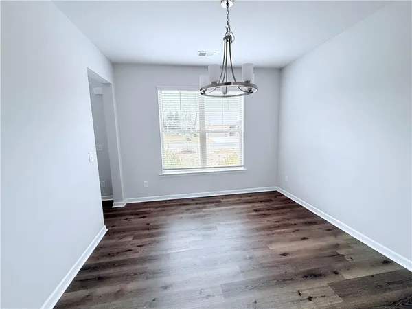 a view of an empty room with wooden floor fridge and a window