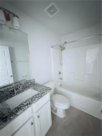a bathroom with a granite countertop sink a toilet and shower