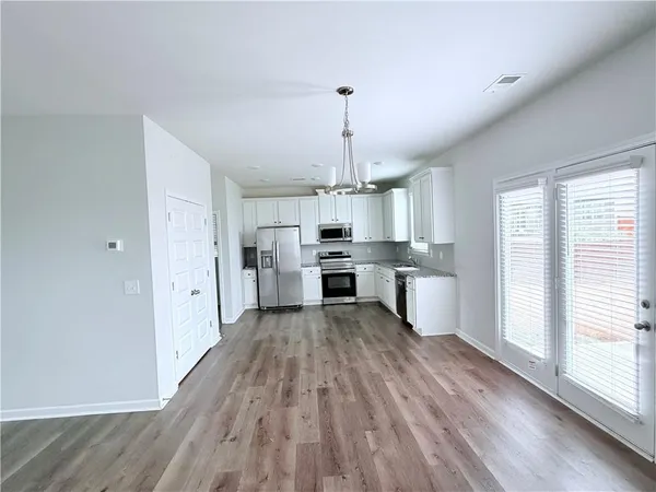 a large kitchen with cabinets wooden floor stainless steel appliances and window