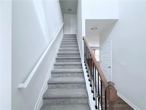 a view of staircase with wooden floor and white walls