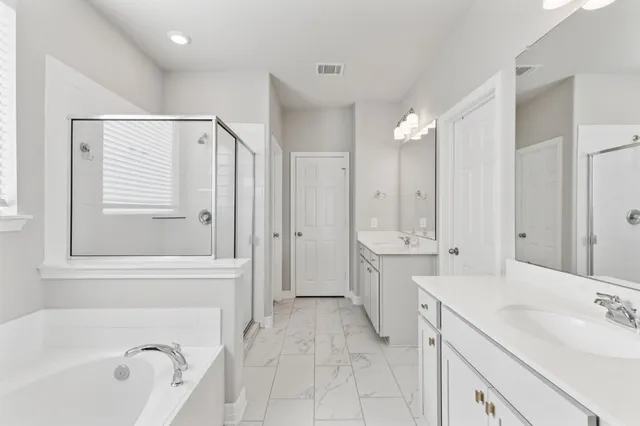 a spacious bathroom with a tub sink shower and mirror