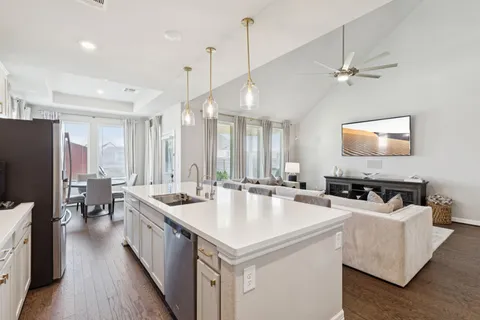 a large kitchen with kitchen island a stove a sink a center island a dining table and chairs