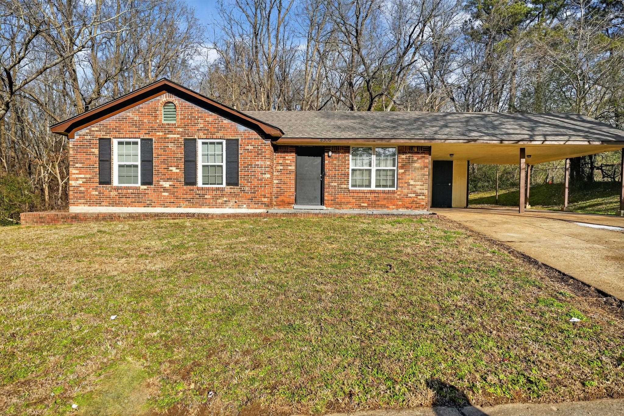 Ranch-style house with driveway, an attached carport, brick siding, and a front lawn
