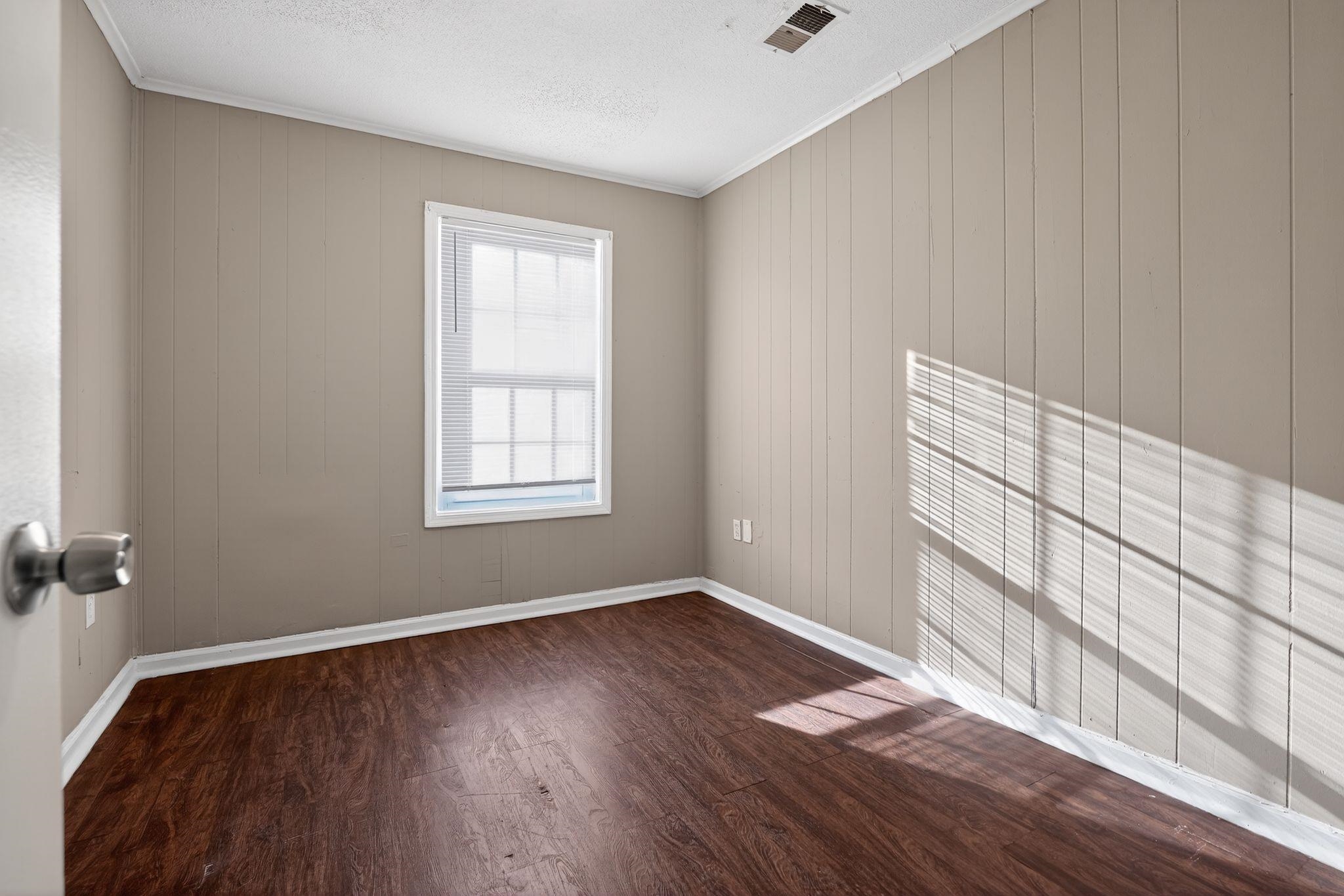 4306 University Street Memphis, TN 38127 - Photo 11 of 26 Spare room with dark wood finished floors, a textured ceiling, and ornamental molding
