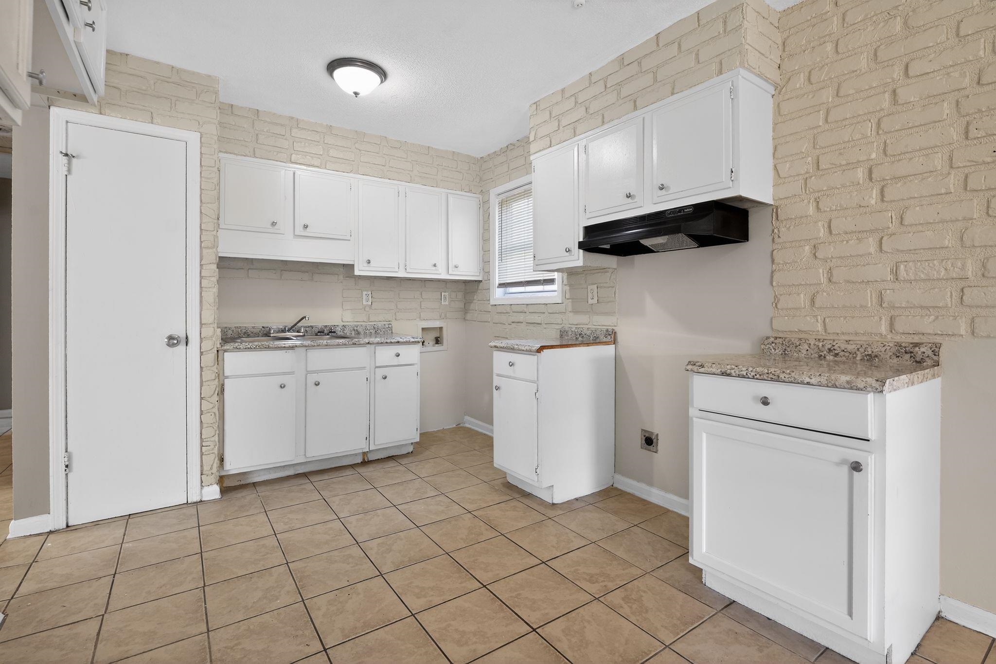 4306 University Street Memphis, TN 38127 - Photo 13 of 26 Kitchen with white cabinetry, under cabinet range hood, light countertops, and tasteful backsplash