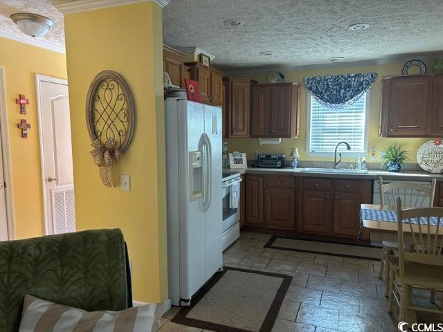 449 East Bank Dr Garden Murrells Inlet, SC 29576 - Photo 18 of 31 Kitchen with a textured ceiling, stone tile floors, white appliances, a sink, and light countertops