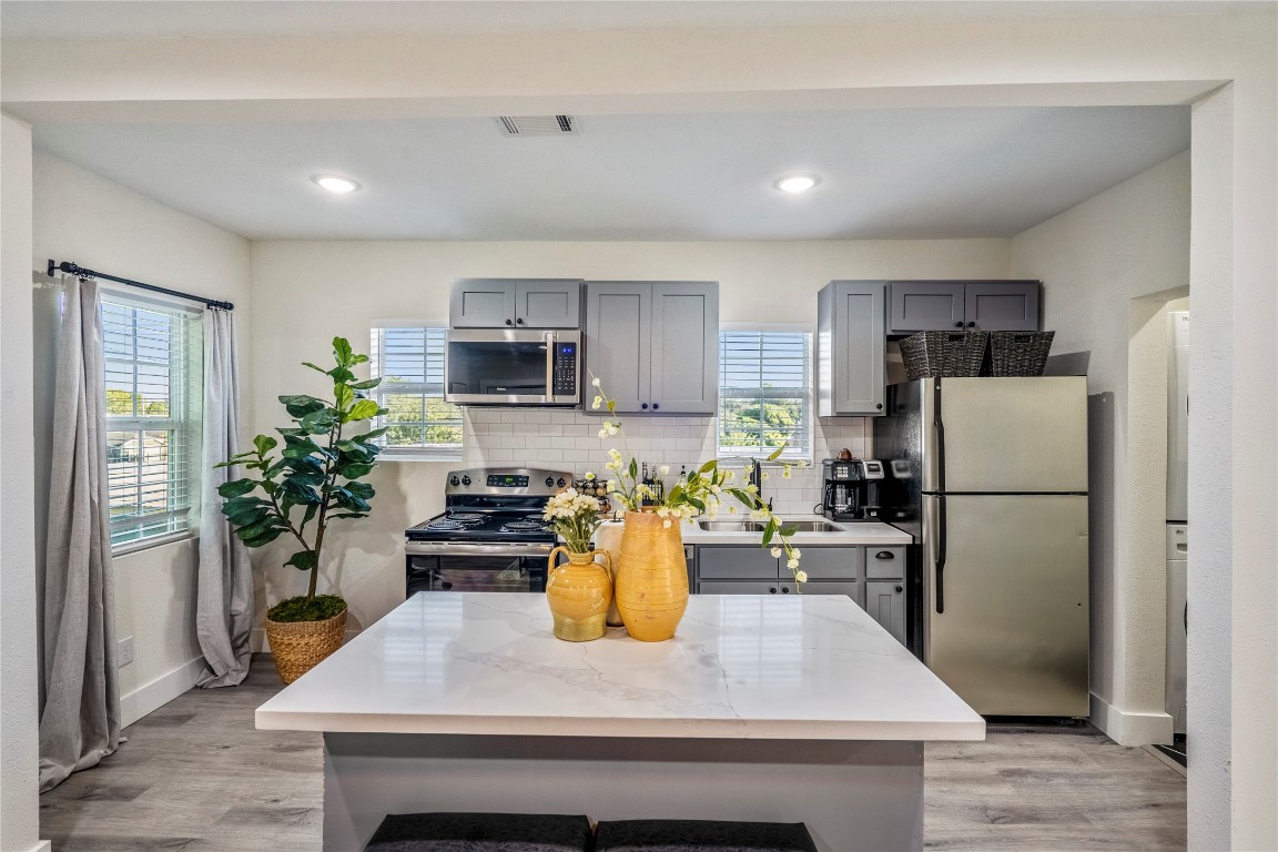 5 Estelle Street, Unit 1 Houston, TX 77003 - Photo 21 of 33 a kitchen with a refrigerator a stove top oven a sink dishwasher and white cabinets with wooden floor