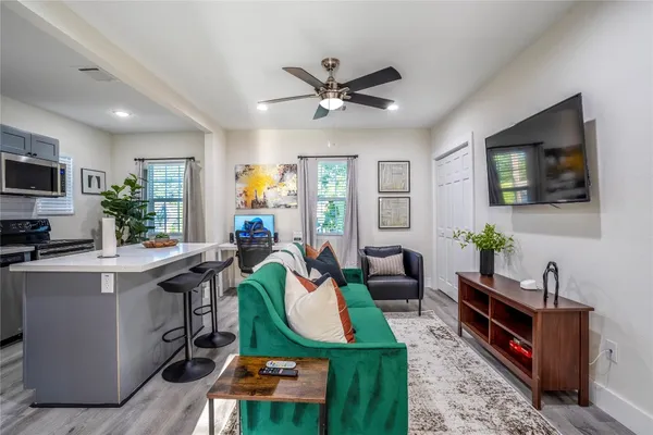 a living room with furniture a flat screen tv and kitchen view
