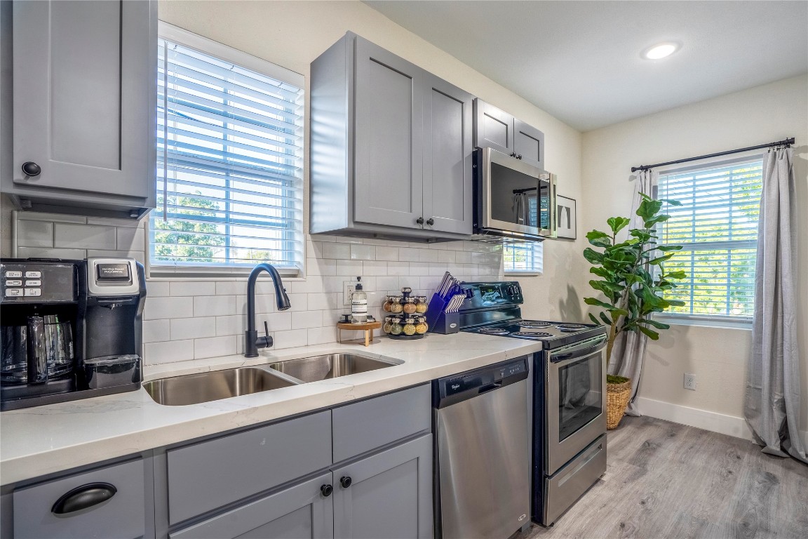 5 Estelle Street, Unit 1 Houston, TX 77003 - Photo 28 of 33 a kitchen with stainless steel appliances granite countertop a sink a stove and a wooden floors