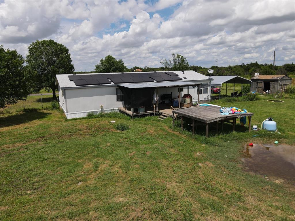 15962 Fritcher Road Pilot Point, TX 76258 - Photo 10 of 24 Rear view of property with a lawn, solar panels, and a detached carport
