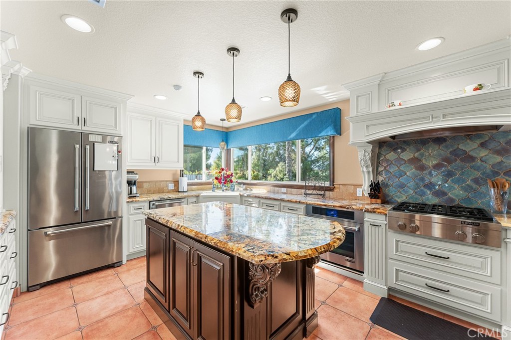 1632 Country Club Drive Redlands, CA 92373 - Photo 8 of 54 a kitchen with stainless steel appliances granite countertop a sink a kitchen island a stove a refrigerator and a center island