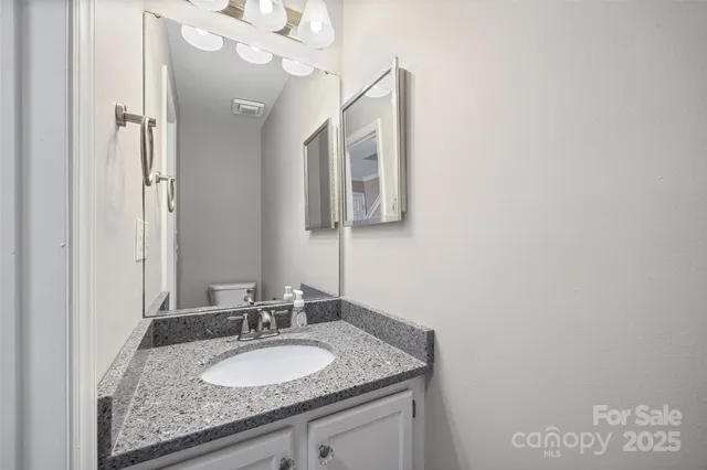 a bathroom with a granite countertop sink a mirror and shower