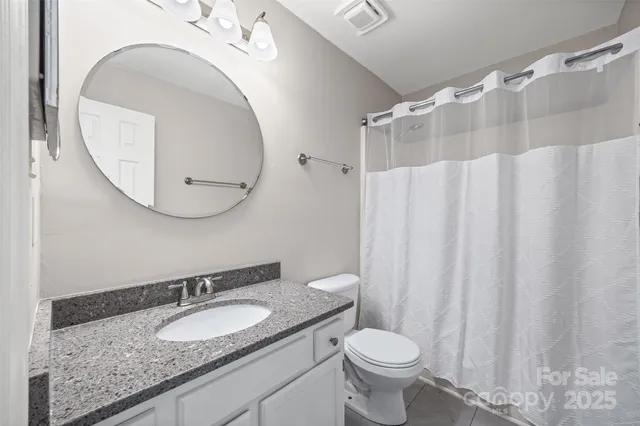 a bathroom with a granite countertop toilet sink and mirror